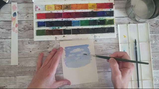L'artiste retire la peinture encore humide avec un pinceau sec pour ouvrir les blancs et faire apparaître des nuages, on voit le pigment soulevé et le blanc du papier réapparaître