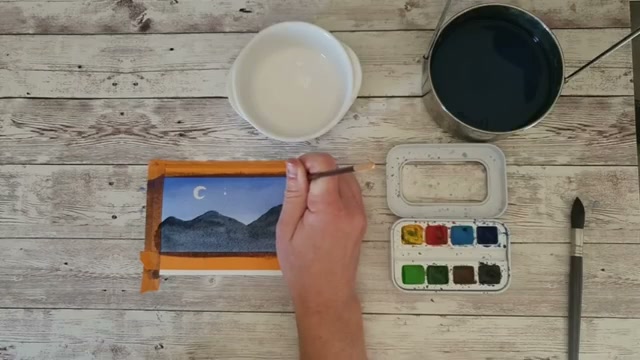 Application de la gouache blanche pour les étoiles à des endroits aléatoires dans le ciel nocturne, avec le croissant de lune déjà peint