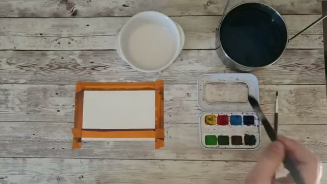 Présentation du matériel avec le pinceau à lavis chargé de bleu outre-mer, on aperçoit la palette et les fournitures utilisées pour le projet