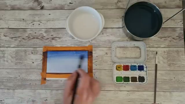 Le dégradé de ciel bleu est en cours de réalisation, le pigment est encore humide et l'artiste montre qu'on peut encore foncer les zones hautes du lavis