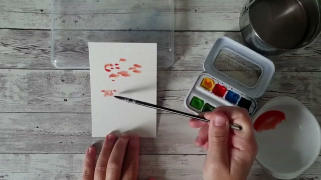 Démonstration du geste de vaporisation sur le papier après avoir posé des touches de couleur au hasard avec le plat du pinceau, avec les espaces blancs visibles
