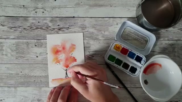 Réalisation des éclaboussures de peinture rouge et jaune autour de l'arbre pour figurer des feuilles qui volent et apporter du mouvement à la composition